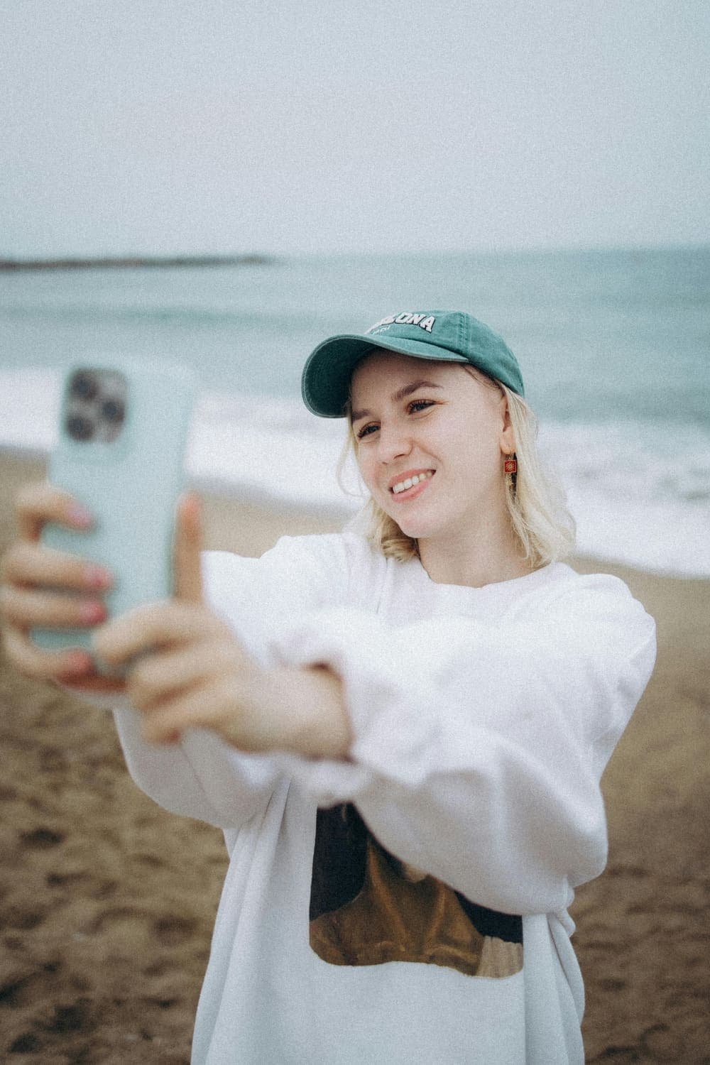 A creator filming a selfie video on her phone at the beach